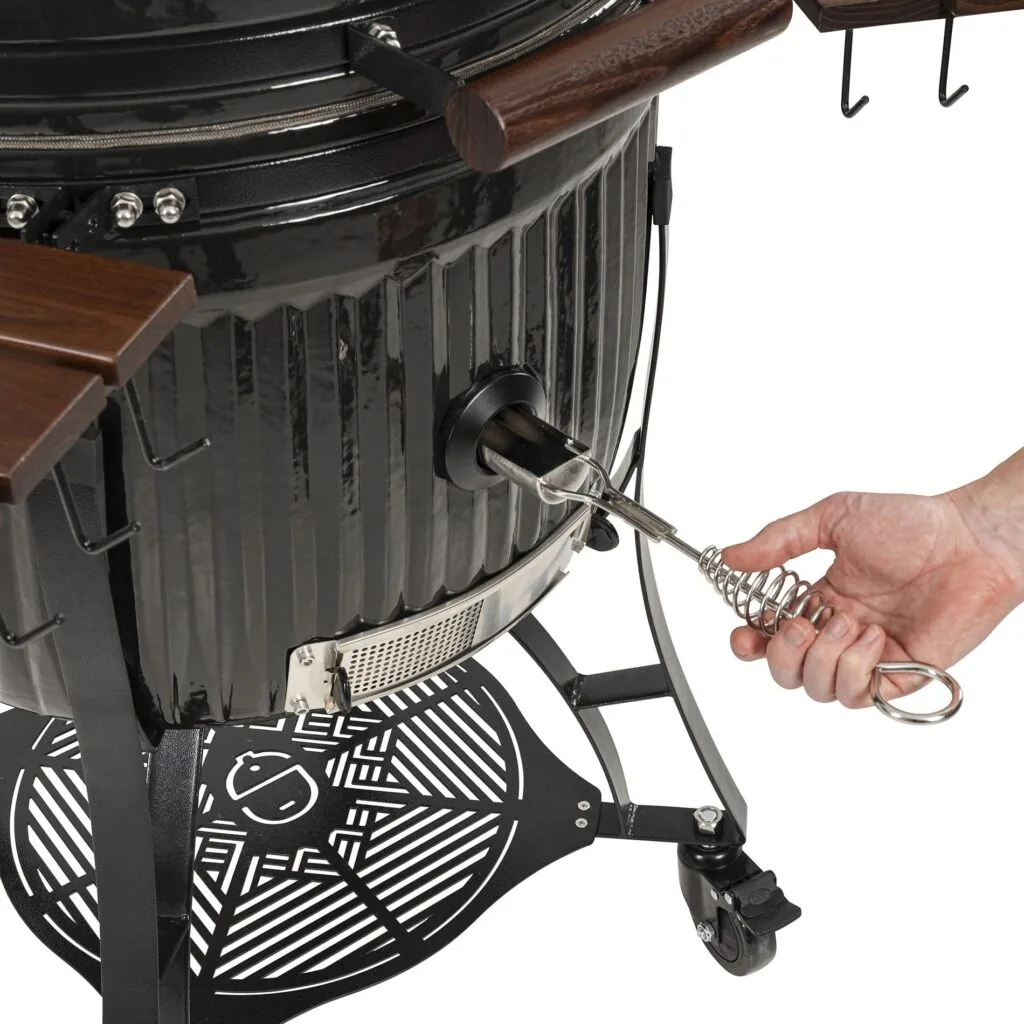 Hand operating the vent of a Kamado Sumo ceramic grill