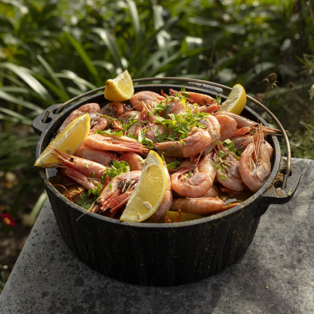 Delicious shrimp dish with lemon and herbs in a cast iron pot