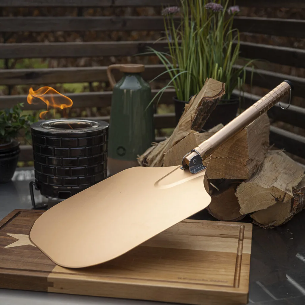 Golden pizza peel resting on a wooden board