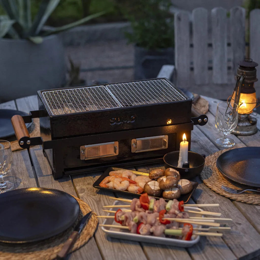 Kamado Sumo hibachi grill with seafood and skewers on a dining table