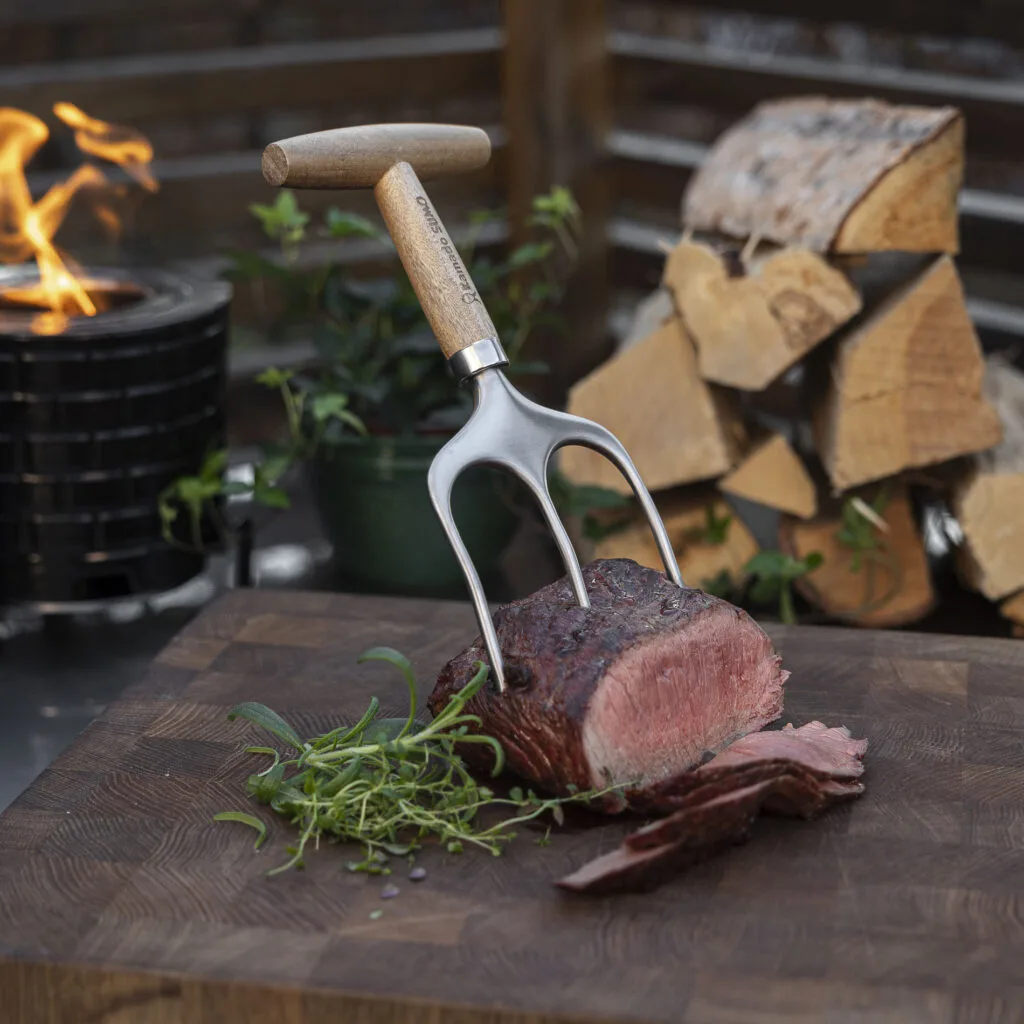 Metal meat fork resting on sliced roast beef