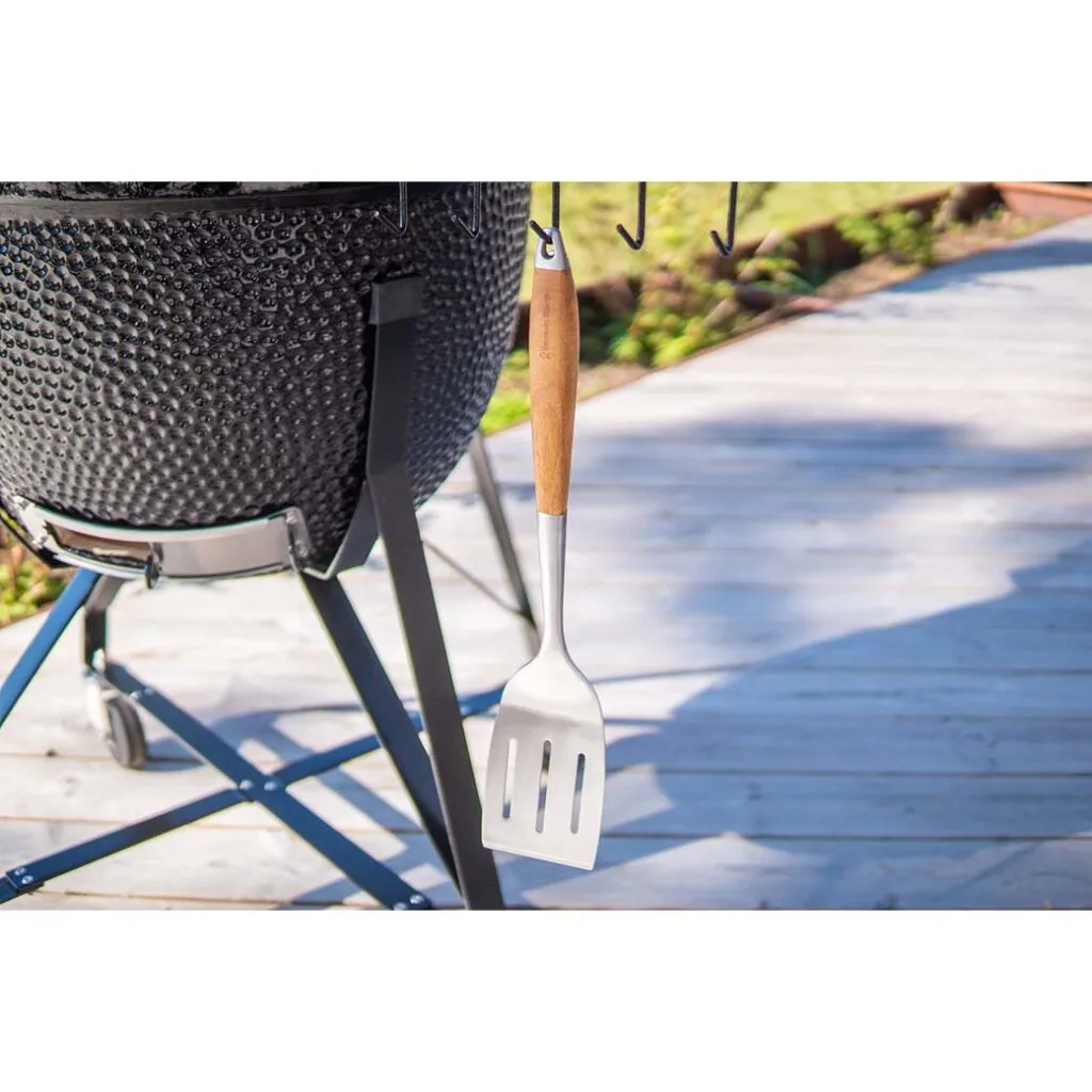 Stainless steel spatula hanging next to a Kamado Sumo ceramic grill