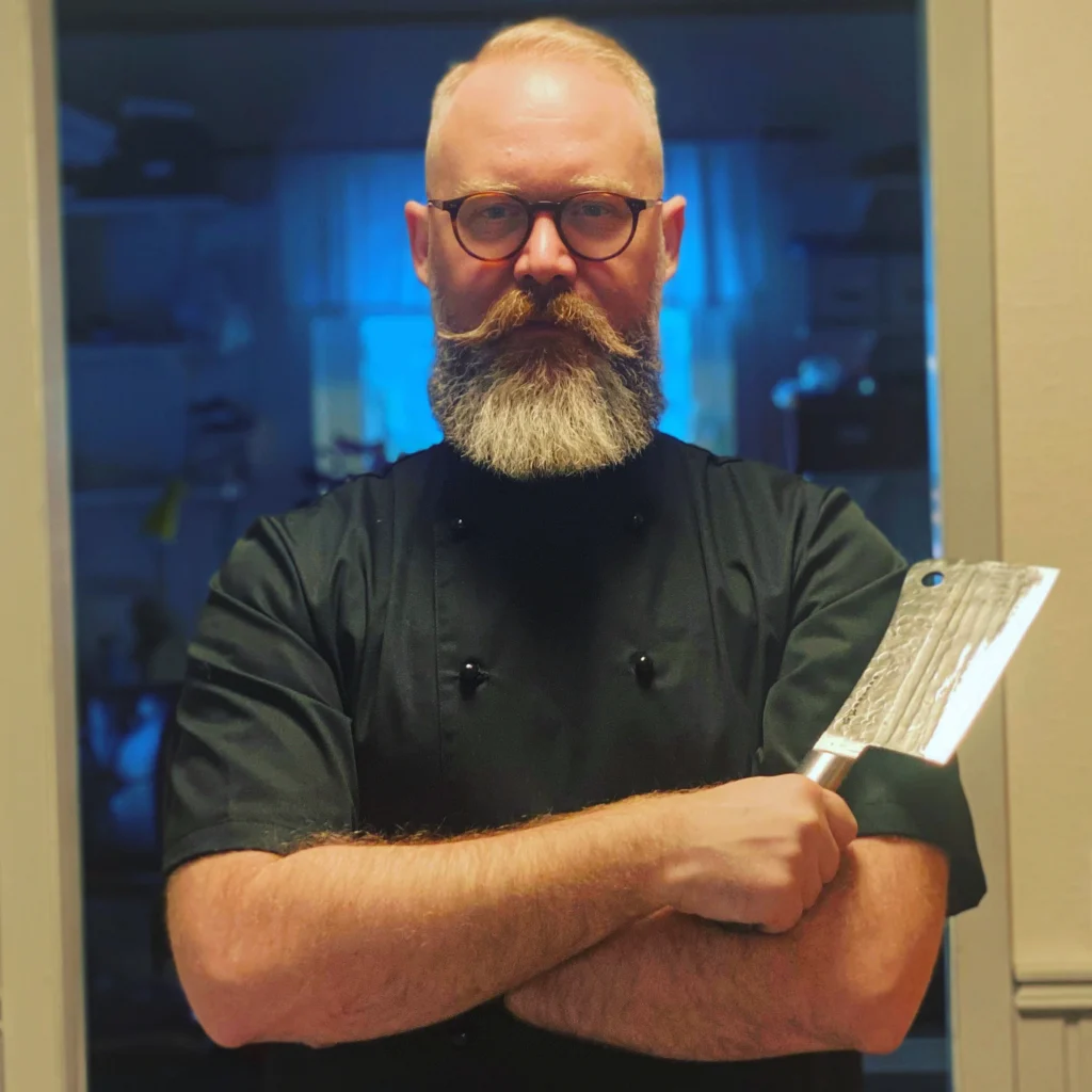 Chef with a beard holding a cleaver